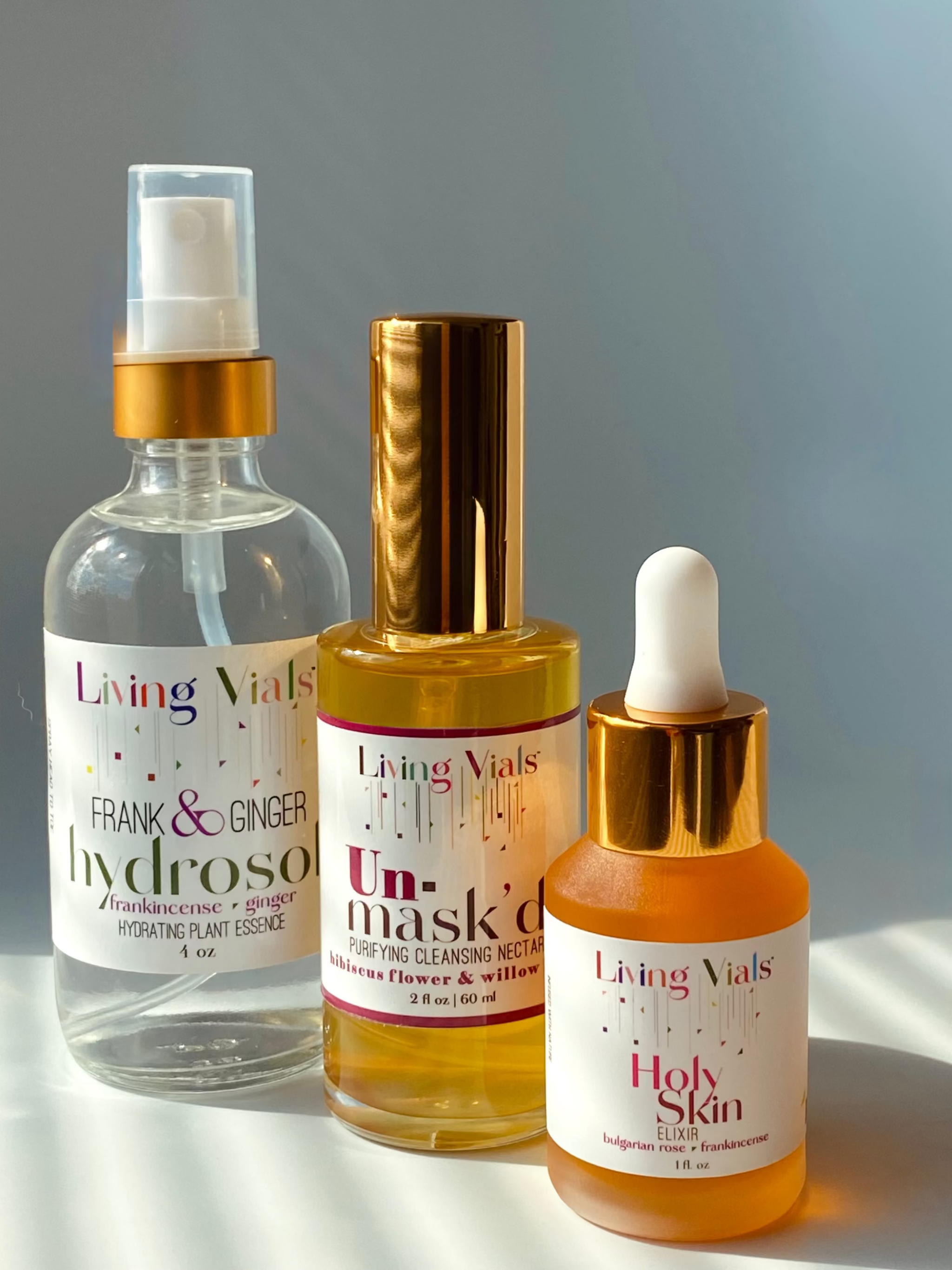 Three bottles of Living Vials skincare products on a gray background